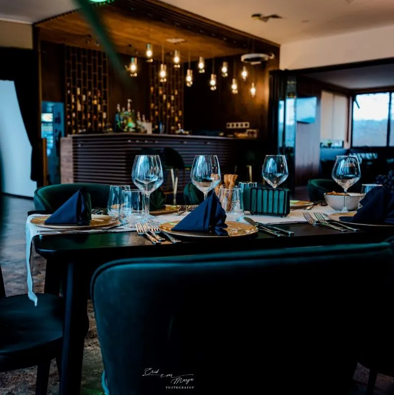 Mese aranjate în restaurantul Poiana Verde, lumină caldă și barul în fundal